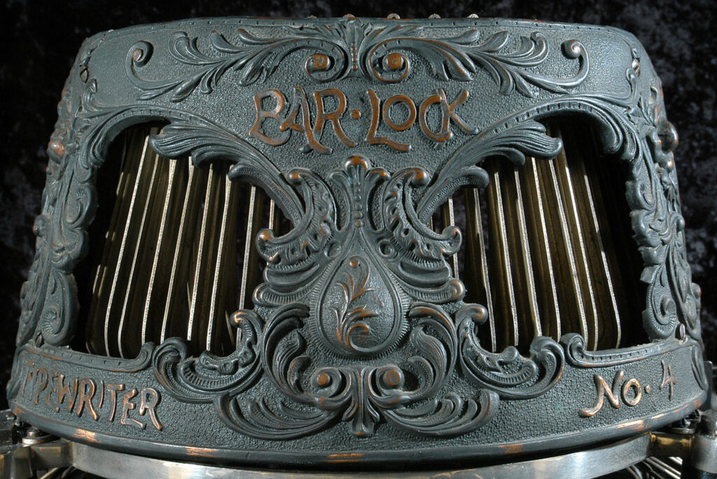 Close up view of the, ornate copper, type-bar shield of the Bar-Lock 4 typewriter.