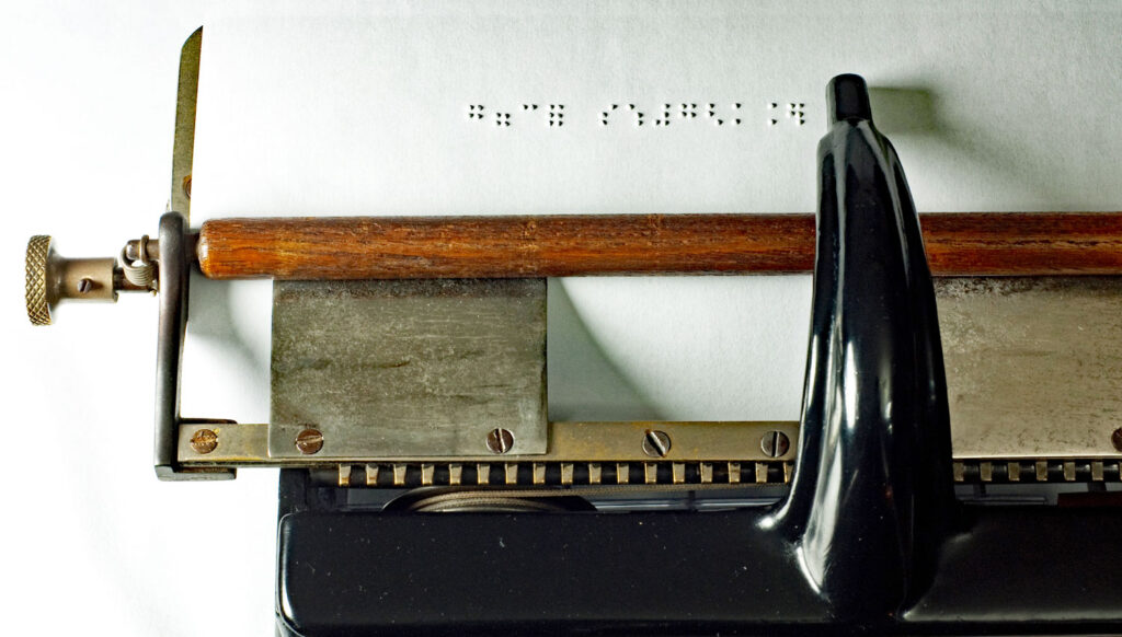 Photograph of the Hall 1 Braille writer typing with the raised braille dots.